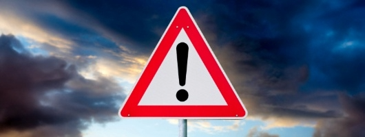 Caution sign with storm clouds in background